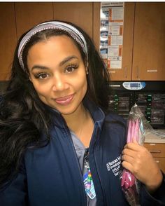 a woman in a blue jacket is holding some toothbrushes and a plastic bag