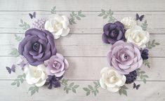 purple and white paper flowers are arranged on a wooden surface