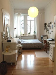 a bedroom with a bed, desk and mirror in it's center area next to a window