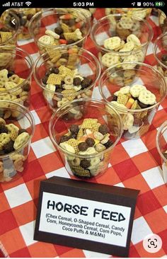 a table topped with lots of cups filled with food next to a red and white checkered table cloth