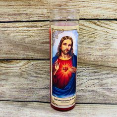 a candle with the image of jesus holding a heart in his hand on top of a wooden table