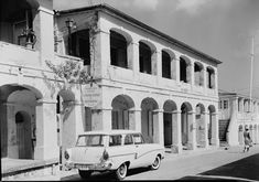 an old white car parked in front of a building on the side of a road