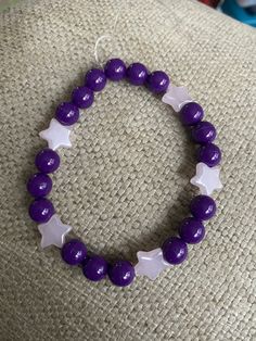 "This beautifully handmade 8mm beaded charm bracelet is strung along clear stretch cord to easily roll onto your wrist. Throughout the bracelet in between dark purple beads are pale pink stars. This bracelet is tied at the end so no need to worry about clips or clasps, this bracelet slides right on! This fits a size 7 inch wrist, but I can adjust if needed. This is a fantastic birthday gift, anniversary gift, Christmas gift, Mother's Day gift, birthday gift, or even a \"just because\" gift! This Braclets Ideas Beaded Purple, Adjustable Celestial Bracelets With Star Charm, Adjustable Star-shaped Celestial Bracelets, Adjustable Celestial Star Bracelet, Adjustable Celestial Beaded Bracelets With Round Beads, Celestial Style Adjustable Beaded Bracelets With Round Beads, Adjustable Stretch Bracelet With Star Charm As Gift, Adjustable Celestial Bracelets With Round Beads, Adjustable Celestial Bracelet With Round Beads