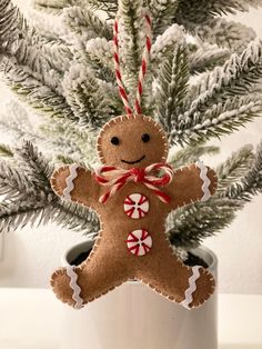 a gingerbread man ornament hanging from a christmas tree in a white pot