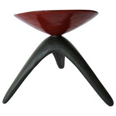 a red bowl sitting on top of a black metal stand with an open foot rest