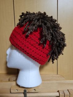 a white mannequin head wearing a red and black crochet beanie