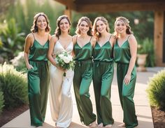 four bridesmaids pose for a photo in their green jumpsuits and white bouquet