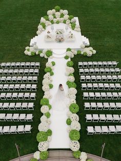 an aerial view of a wedding ceremony setup with white chairs and green topiary on the lawn