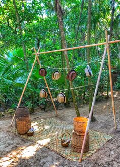 an outdoor area with pots and pans hanging from a line in the woods, surrounded by palm trees