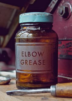 a jar filled with honey sitting on top of a wooden table next to a wrench