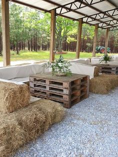 hay bales are stacked on top of wooden pallets under a covered patio area