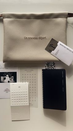 a white purse sitting on top of a table next to a calendar and other items