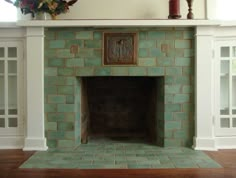 a fireplace in a living room with green tiles and white trim on the mantel