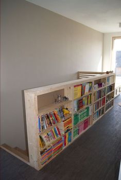 the bookshelf is made out of plywood and has many different colored books