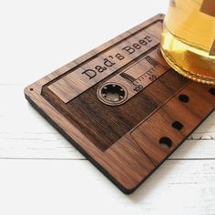 a wooden coaster with an audio tape on it and a glass of beer next to it