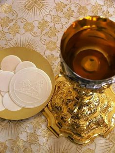 some white and gold coasters sitting on a table next to a metal cup with liquid in it