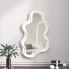 a white mirror sitting on top of a table next to a vase filled with flowers