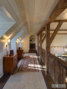 the hallway is very long and has wooden beams on the ceiling, along with an area rug