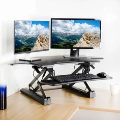 two computer monitors sitting on top of a wooden desk