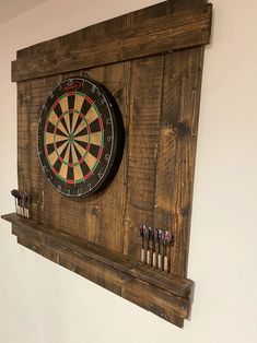 a dart board mounted to the side of a wooden wall with darts on it,