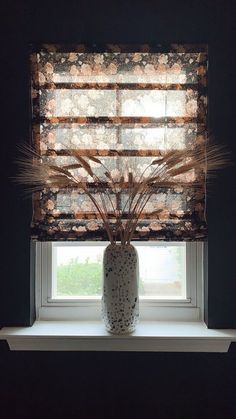 a white vase sitting on top of a window sill next to a window covered in blinds