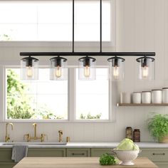 a kitchen island with lights hanging from it's ceiling and an open window in the background