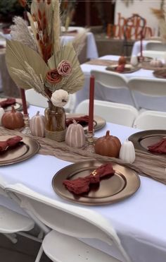 the table is set with plates, napkins and candles for an elegant fall dinner