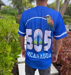 Nicaragua Baseball Jersey in classic blue. This short-sleeve, button-up jersey features high-quality sublimation printing of the Nicaraguan coat of arms on the front, a proudly displayed flag on the sleeve, and the iconic "505" on the back, symbolizing Nicaragua’s roots. Sublimated Coat of Arms Design: Showcases Nicaragua's heritage with vibrant detail. Iconic "505" on Back: Represents Nicaragua’s international calling code. Flag Patch on Sleeve: Adds an authentic touch of national pride. Comfor Blue T-shirt With Letter Print For Outdoor, Blue Short Sleeve T-shirt For Outdoor, Blue Printed Shirt For Streetwear, Blue Custom Print Shirt For Streetwear, Printed Light Blue Short Sleeve T-shirt, Outdoor Blue T-shirt With Letter Print, Blue Casual T-shirt With Custom Print, Blue Crew Neck Shirt For Outdoor, Casual Blue T-shirt With Custom Print