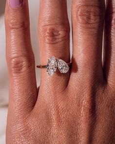 a woman's hand with a ring on it and two diamonds in the middle