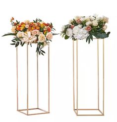 two tall vases with flowers in them on white background, one is gold and the other is orange