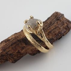 a close up of a ring on top of a piece of driftwood with a white background