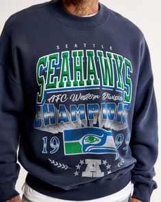 Elevate your game day ensemble with the Men's Seattle Seahawks Graphic Crew Sweatshirt from Abercrombie & Fitch. This navy blue textured sweatshirt is a must-have for any Seahawks fan looking to showcase their team spirit in style.  - Size: Medium - Color: Navy Blue Texture - Material: Cotton, Polyester - Gender: Male - Features: SoftAF fleece fabric, oversized-fit silhouette, vintage Seattle Seahawks-inspired graphic, crew neckline, banded hem and cuffs  Perfect for chilly game days or casual w Navy Blue Texture, Seahawks Fans, Blue Texture, Men's Tops, Atlanta Falcons, Seattle Seahawks, Crew Sweatshirts, Fleece Fabric, Oversized Fits