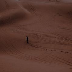 a lone person standing in the middle of an empty field at night, surrounded by sand dunes