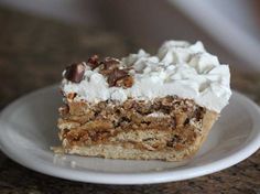 a piece of cake with white frosting and nuts on top sitting on a plate