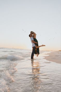 a man holding a woman on his back while standing in the water at the beach