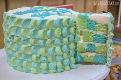 a cake with blue and green frosting is on a table next to another cake