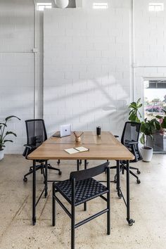 a table and chairs in an office with white brick walls, plants and potted plants