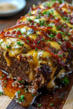 a meatloaf with cheese and bacon is on a cutting board next to a fork