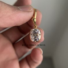 a person holding a diamond in their left hand and wearing a yellow gold pendant on the other hand