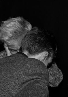 black and white photograph of two people hugging each other with one woman covering her face