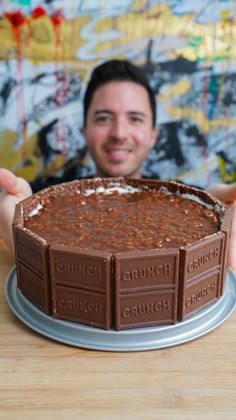 a man is holding up a chocolate cake