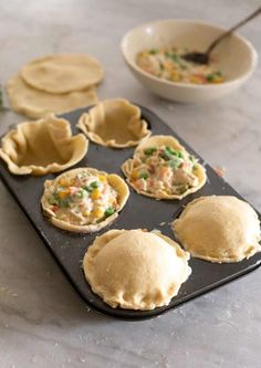 several small pies sitting on top of a cookie sheet with some toppings in them