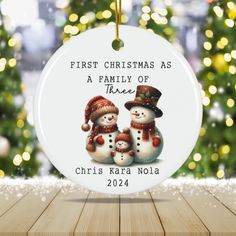 a christmas ornament with two snowmen on it and the words first christmas as a family of three