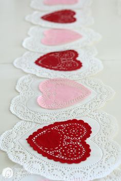 valentine's day doily hearts are lined up on a table with pink and red accents