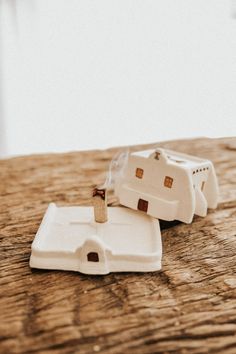 two pieces of white pottery sitting on top of a wooden table next to each other