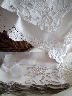 several pieces of white linen with lace on them and some folded napkins next to each other