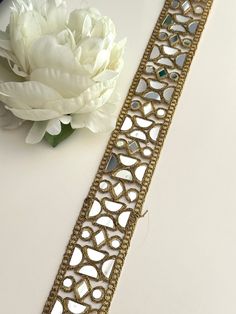 a white flower sitting on top of a table next to a gold bracelet with hearts