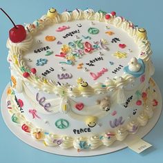 a cake with white frosting decorated with letters and a cherries on the top