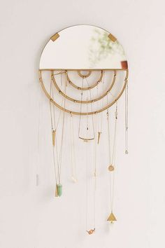 a circular mirror hanging on the wall next to a white wall with gold and green decorations