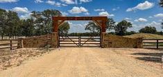 an open gate in the middle of a dirt road